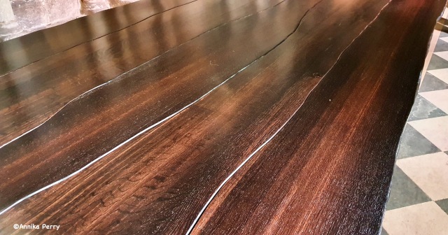 "A cross-section of the table, showing the varying sheen of dark to light brown surface and highlighting the beautiful sweeping planed wood."