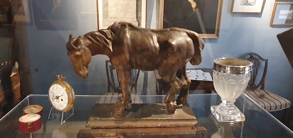 "Constables model horse surrounded by other memorbila such as glass and watch."